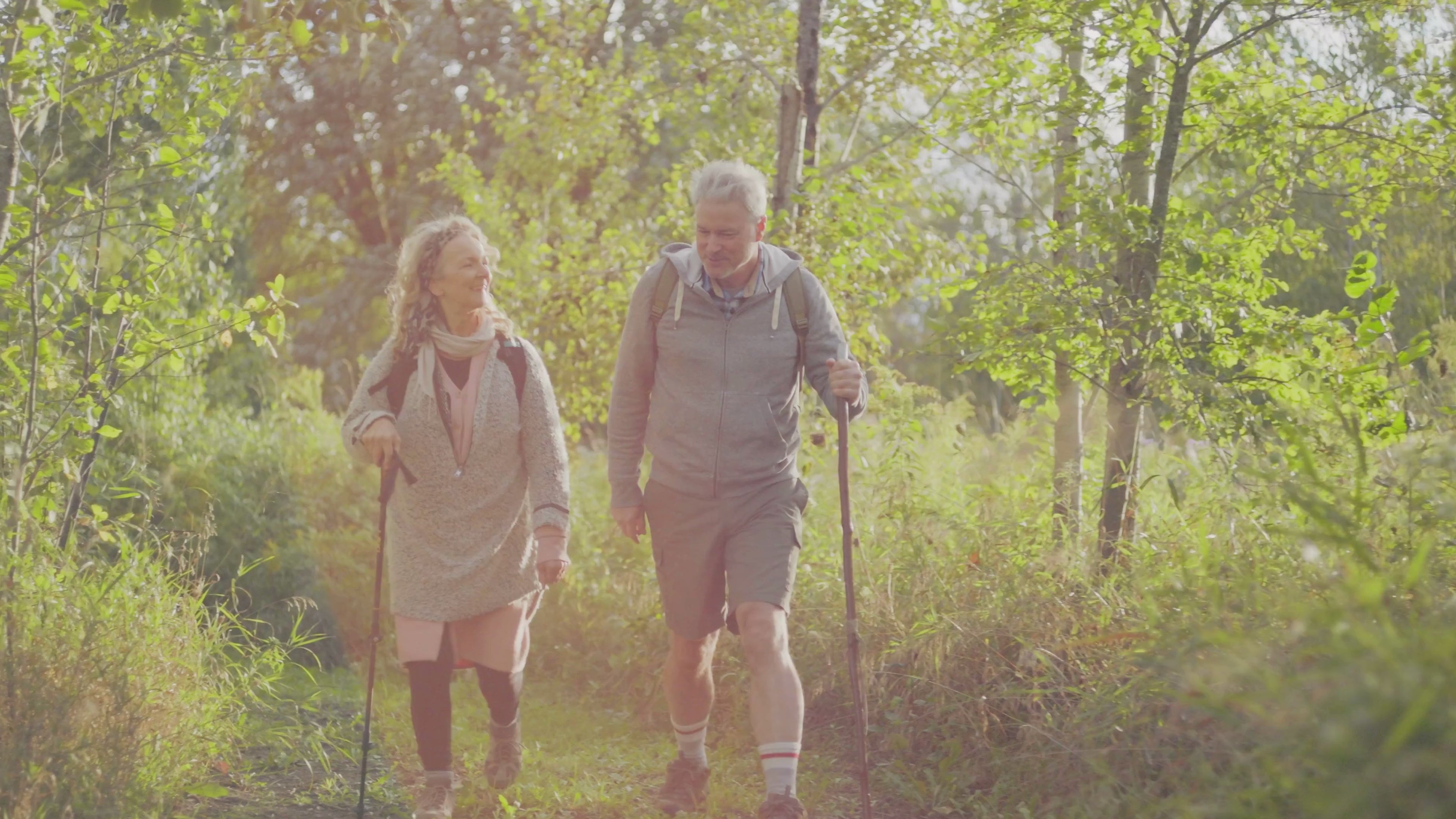 Woman and man in their early 60s rucking with a backpack and poles